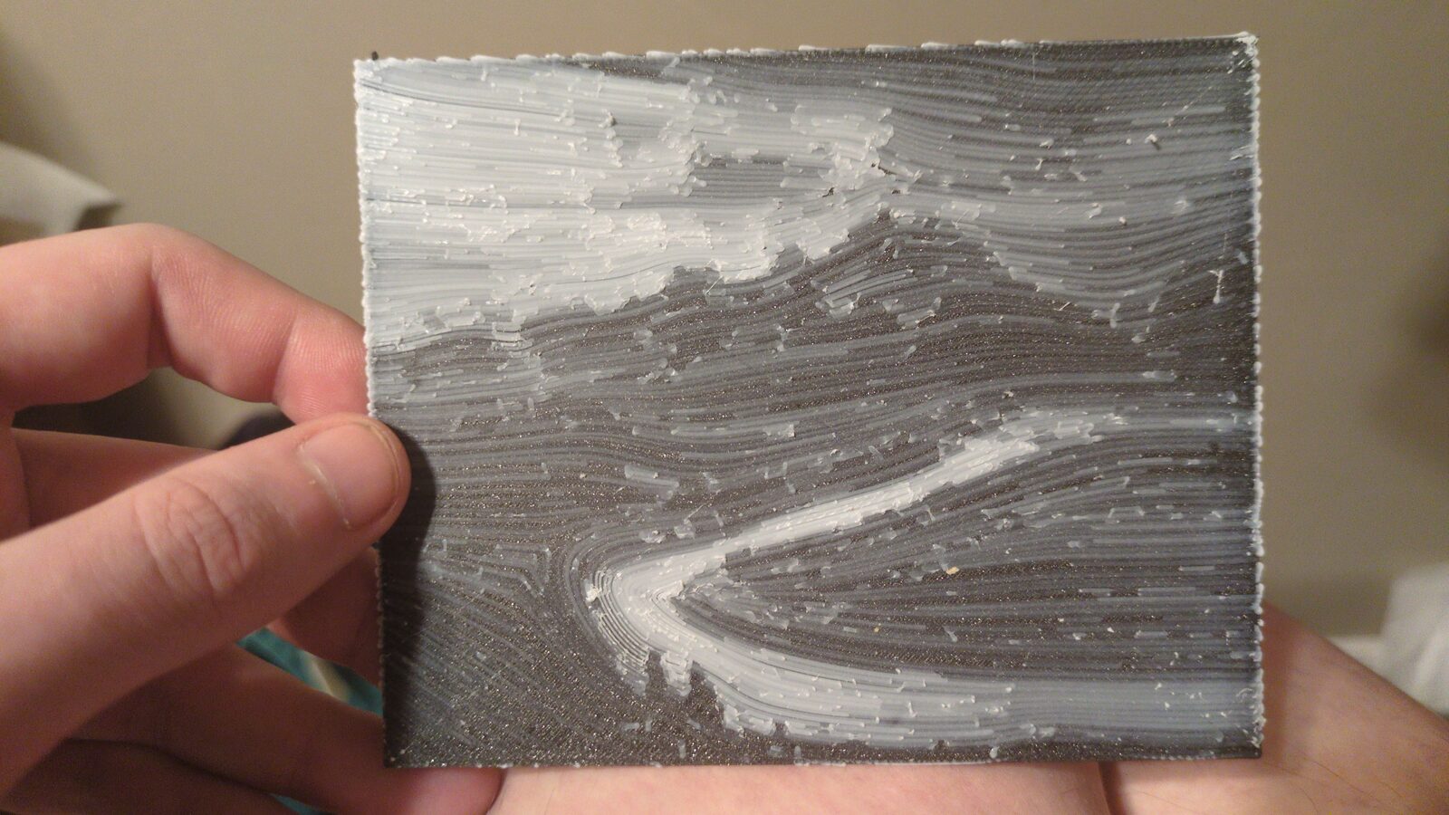 The Tetons printed in flowing white lines on black, held in a hand
